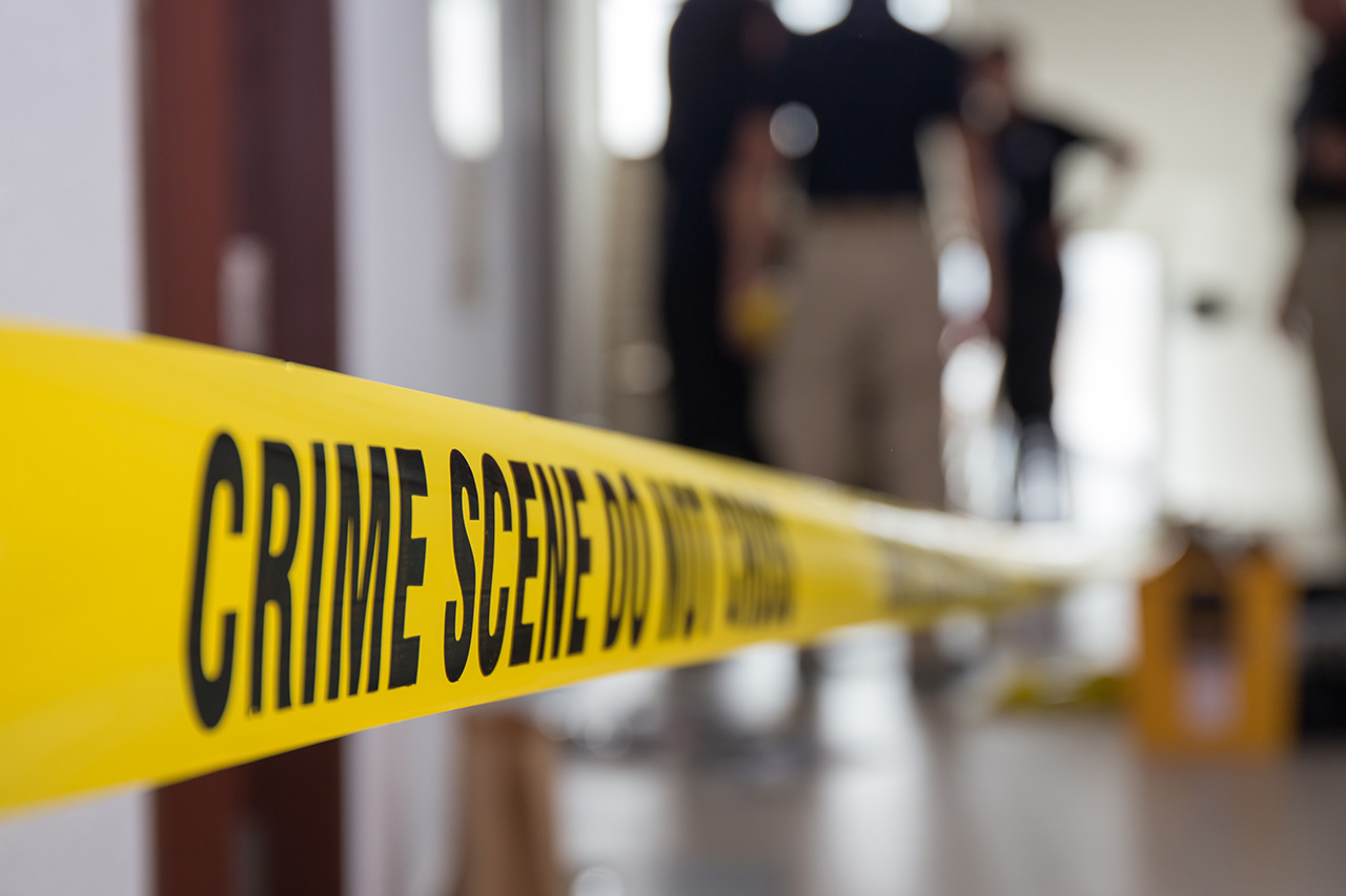 Crime scene tape in building with blurred forensic team background